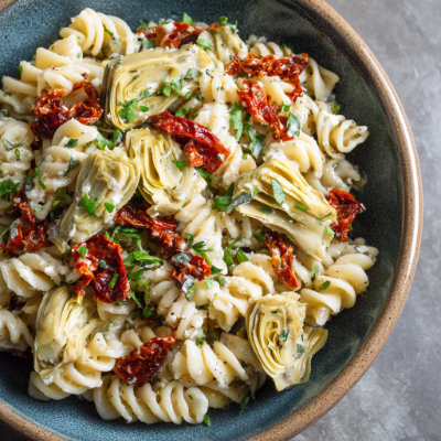 A bowl of pasta with artichoke hearts.