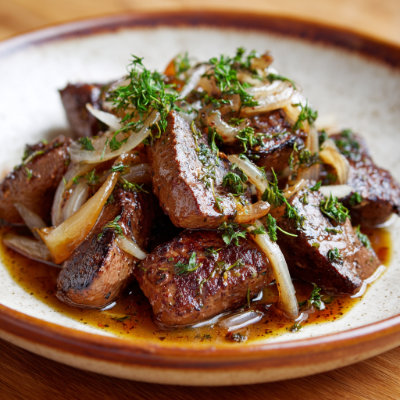 A slice of cooked beef liver with onions.