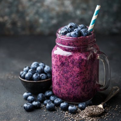 A purple smoothie in a glass with a straw.