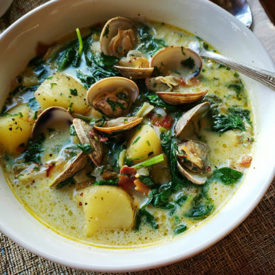 A creamy chowder with clams and spinach, on a white background with a NutrientShield logo.