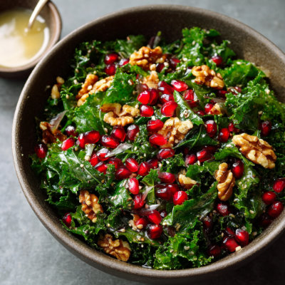 A kale salad topped with pomegranate seeds.
