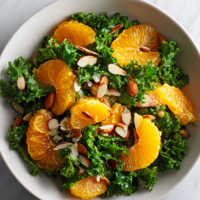 A colorful salad with orange segments, kale, and almonds, on a white background with a NutrientShield logo.