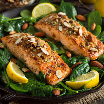 A fresh salad with grilled salmon, spinach, and almonds, on a white background with a NutrientShield logo.