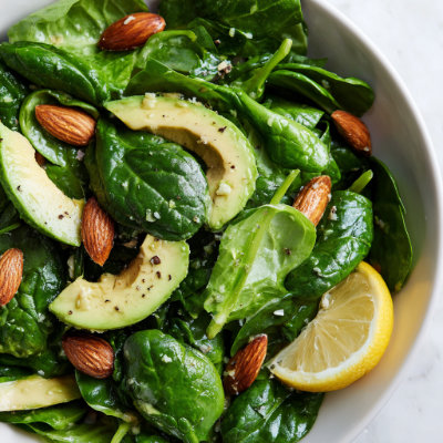 A salad with fresh spinach, avocado, and almonds.
